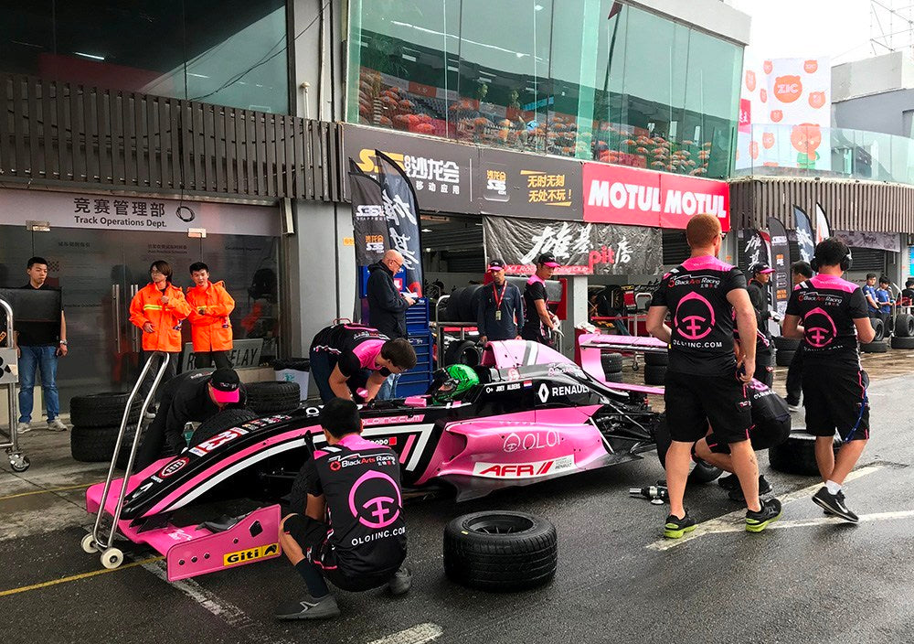 BlackArts Racing crew changing the tires on the pink Oloi Formula Renault car in wet conditions